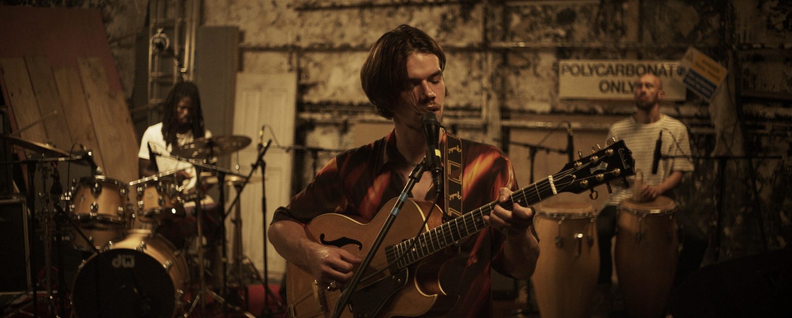 Image of musician Oscar Jerome playing guitar and singing